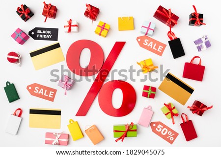 Top view of percent sign with credit cards and toy shopping bags on white background