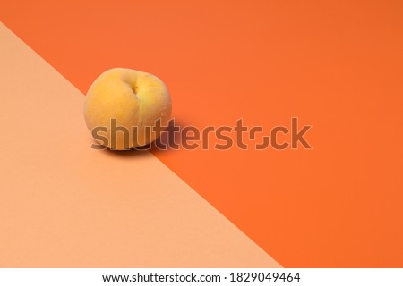 A ripe peach on orange and soft pastel split background