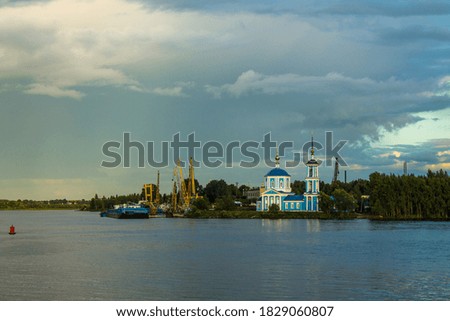 Dramatic landscape-Orthodox Church and green trees on the Bank of the Volga river with reflection on the background of a stormy sky with beautiful clouds and rainbow