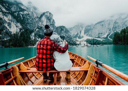 Romantic couple on a boat visiting an alpine lake at Braies Italy. Tourist in love spending loving moments together at autumn mountains. Concept about travel, couple and wanderust.