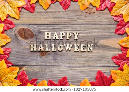 Halloween postcard. The inscription in letters on a wooden background inside a circle made of maple leaves