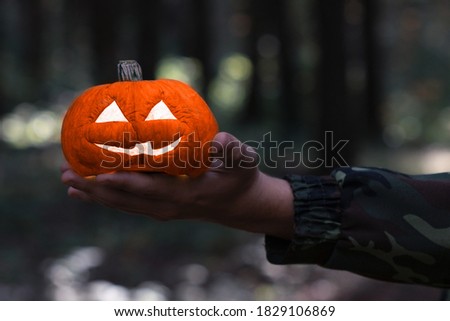 Jack o lantern glowing with moonlight in an eerie night forest.Halloween dark background with burning orange pumpkin that a men holds on his hand.Happy Halloween banner. Copy space for text