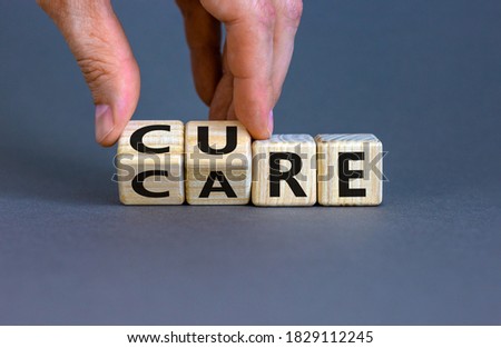 Hand is turning cubes and changes the word 'CARE' to 'CURE'. Beautiful grey background. Business and medical concept, copy space.