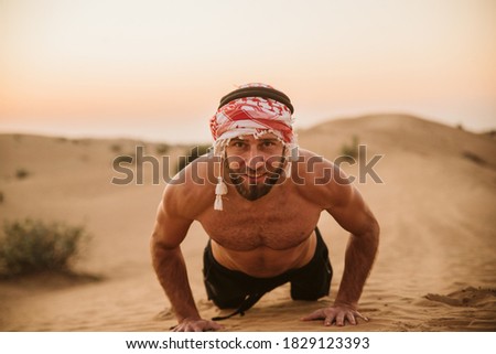 A portrait of a handsome muscular man doing push-ups in the desert