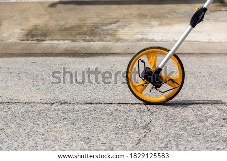 Distance measuring wheel device. Rolling distance measurement tool. Construction measuring tool. Measuring wheel tool for calculating distance. Outdoor surveying measurement tool with rolling odometer Royalty-Free Stock Photo #1829125583