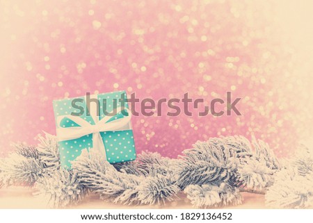 Blue gift box with frosty fir tree branches over pink background with copy space. Vintage style edited photo