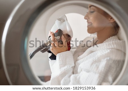 Side view of happy woman receiving oxygen therapy at hyperbaric chamber at health spa.  Royalty-Free Stock Photo #1829153936