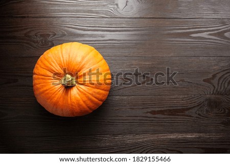 Autumn fresh pumpkin on dark wooden background, top view with copy space. Autumn vegetables.