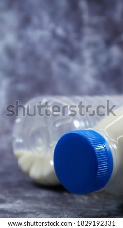 A plastic bottle of fresh regular milk on a dark gray marbled or concrete background. Close-up front view. World milk day concept. Nutrient fluid. Vertical photography.