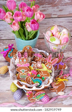 easter table decoration with handmade gingerbread cookies in basket  on old wooden background