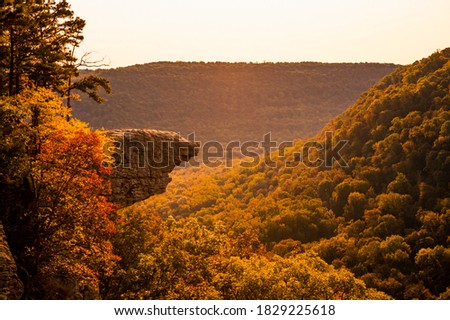 The sun rises over Whitaker Point, known as Hawksbill Crag, in Arkansas as the fall colors begin to set in on the trees Royalty-Free Stock Photo #1829225618