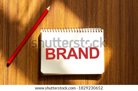 Red pen and notepad with text BRAND in the white background