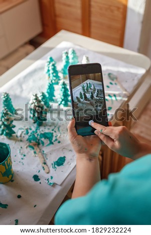 DIY craft gifts and Christmas decoration. Cute girl making photo of handmade green cones to show friends in social network, new normal and social distance celebration, zero waste holidays