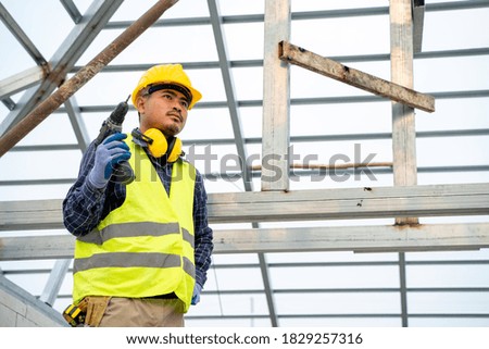 Construction worker using electric drill on house build.