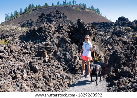 Woman walking a black labrador retriever dog in Lava Lands Newberry Volcano National Monument