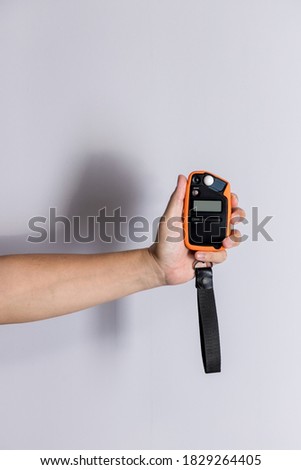 Hand holding light exposure meter, a photograph device for measuring illumination on white background. Hand held light meter isolated in studio lights. 