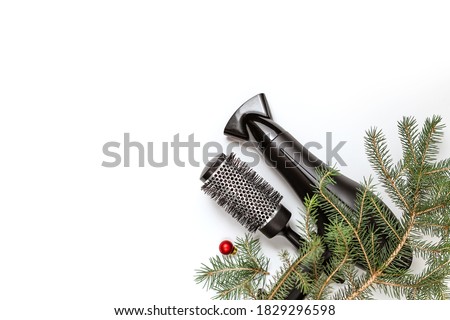 Christmas composition. Hairdressing tools and a spruce branch on a white background, hair dryer, comb. Template for a postcard or information about a hair salon. Flat lay, copy space