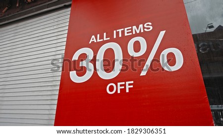 White text on a red banner standing on the street with the inscription 30% off