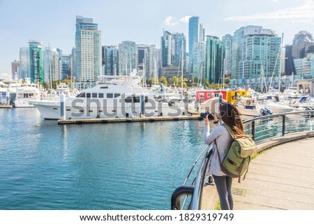Vancouver Canada tourist woman taking picture with camera at Coal Harbour on summer holidays in canadian city. Urban lifestyle.
