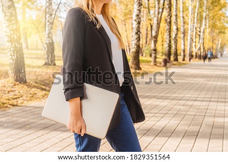 Young woman hold laptop in park, close up. Remote work concept. Only body and laptop on photo, copy space.