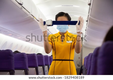 An operator in yellow demonstrates how to fasten seat belts in the aircraft cabin.