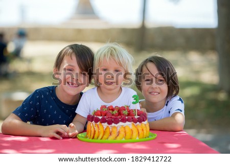 Sweet little blond toddler boy, celebrating his third birthday in a park, outdoors
