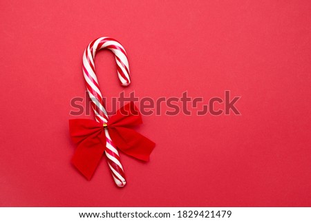 Candy cane with bow on red background with copy space