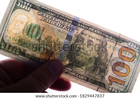 Photographed in this way 100 US dollars in a backlight that two sides of the bill are visible at once, as well as watermarks and protection against forgery