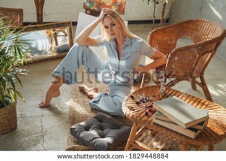 Peaceful and cosy living room with styled bamboo furniture and glamour girl with blond hairs which relaxing in it in sunshine.