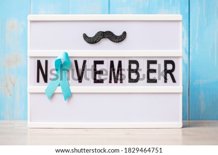 Prostate Cancer Awareness month, Light blue Ribbon with mustache on lightbox with November text background for supporting people living and illness. International Men day and World cancer day concept