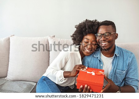 Cheerful young woman receiving a gift from her boyfriend. Excited woman opening a present for their anniversary that her partner just gave her. Gifts given from the heart