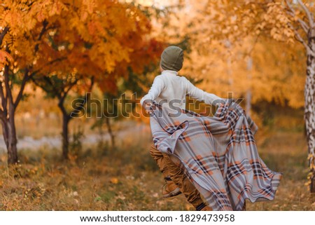 Happy seven-year-old boy in sweater and brown suit runs around in park in fall. blurry picture of the movement