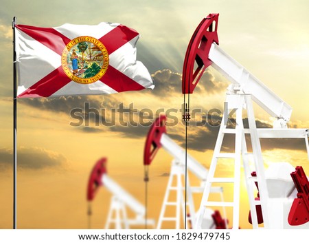 Oil rigs against the backdrop of the colorful sky and a flagpole with the flag State of Florida. The concept of oil production, minerals, development of new deposits.