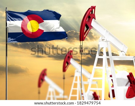 Oil rigs against the backdrop of the colorful sky and a flagpole with the flag State of California. The concept of oil production, minerals, development of new deposits.