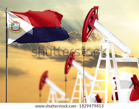 Oil rigs against the backdrop of the colorful sky and a flagpole with the flag of Saint Martin. The concept of oil production, minerals, development of new deposits.