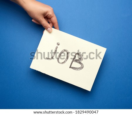 piece of paper with the inscription job, concept of unemployment against the backdrop of the global crisis, fired employee, hand on a blue background 