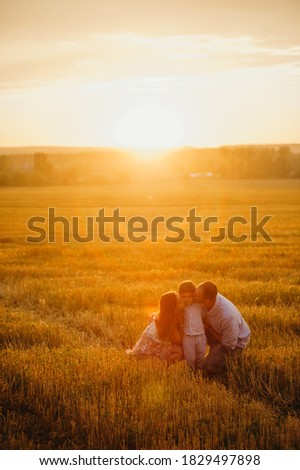 The concept of a happy family. Son with mom and daddy. Happy family in the field evening light of a sun. Mother, father and baby son happy walk at sunset, parents hold the baby. 