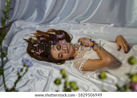 Portrait of a beautiful young woman in a white dress with floral makeup and in flowers