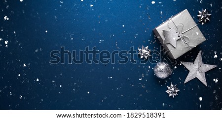 Merry Christmas and Happy Holidays greeting card, frame, banner. New Year. Noel. Silver Christmas gifts, ornaments on blue background top view. Winter holiday xmas theme. Flat lay. Royalty-Free Stock Photo #1829518391