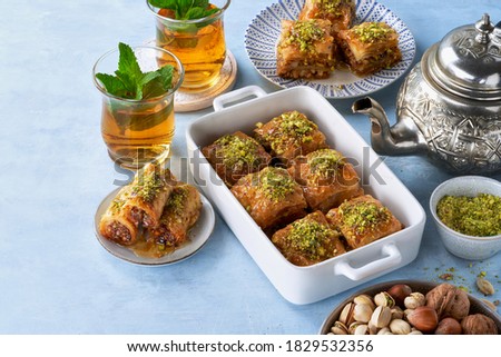 Baklava, Middle eastern different delights, dried dates, pistachios, honey, mint tea on a light blue background. Selective focus. Ramadan.