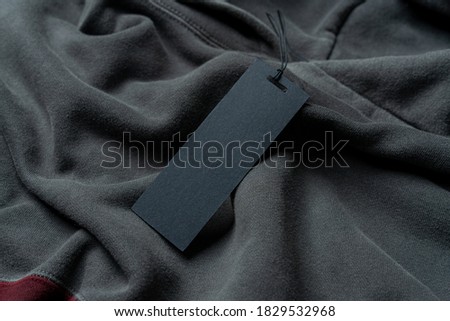 Blank Black Rectangular Clothing Tag, Label Mockup Template on Gray And Tile Colored Stylish Sportswear. Price Tag Label With Copy Space, Empty Space.