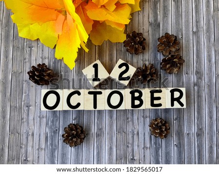 October 12.October 12 on wooden cubes.Cones and autumn leaves on a wooden background.Autumn .Calendar for October.
