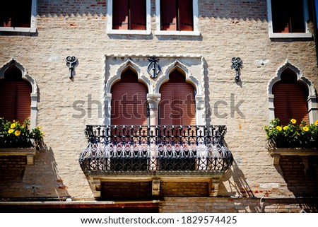 The window and balcony are made in the Moorish style, decorated with yellow flowers in pots and wrought-iron bars.