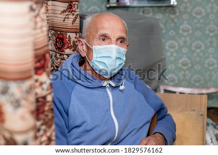 aged adult man in medical blue face mask sitting at home in quarantine healthcare concept