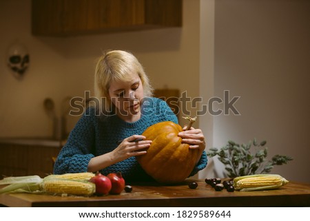 Young woman drawing face on pumpkin for halloween