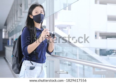 woman traveler with protection mask and backpack , holding camera
