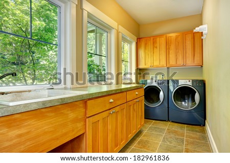 Narrow laundry room with wooden cabinets, washer and dryer