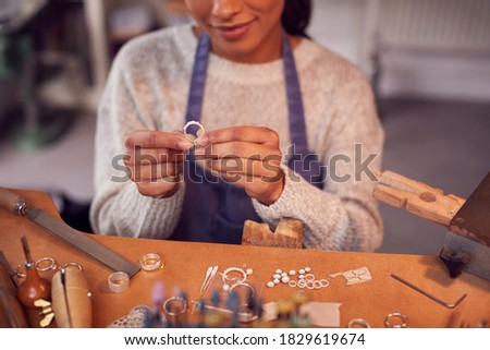 Close Up Of Female Jeweller At Bench Checking Ring She Is Working On In Studio Royalty-Free Stock Photo #1829619674