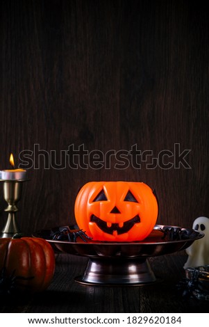 Close up of spooky Halloween tricks, concept of horror festival decor, pumpkin lantern with candlestick and smoke.