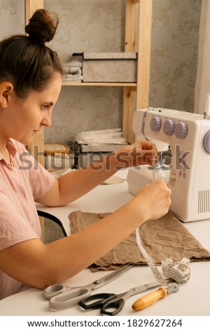 a beautiful caucasian woman measures a piece of fabric with a centimeter ribbon, sewing concept